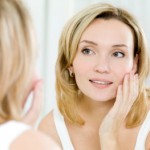 The beautiful young girl with a clean fresh skin touches with a hand a cheek